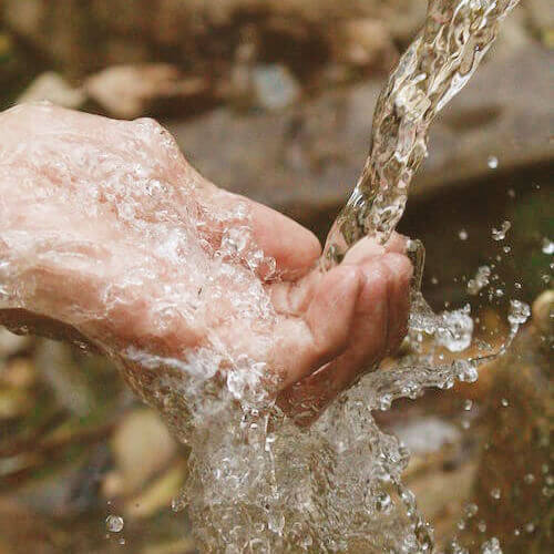 Hand unter fließendem Wasser am Fluss